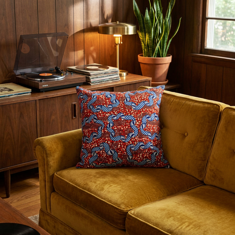 Red and blue African print pillow cover on a vintage mustard velvet sofa beside a record player