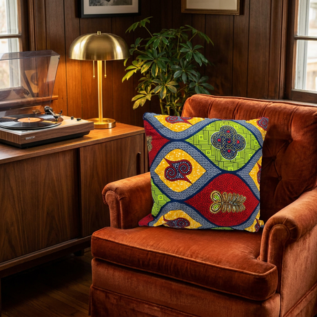 Multicolor African print pillow cover on a vintage rust velvet armchair beside a record player