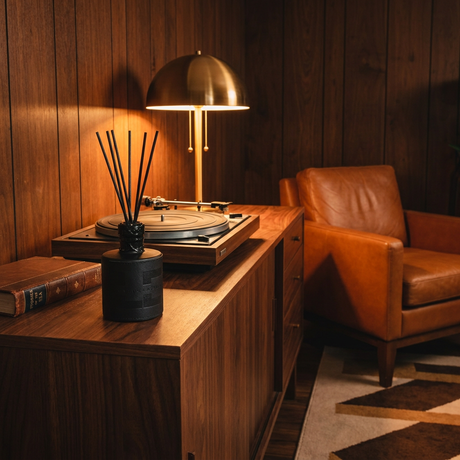 Leather scent reed diffuser on a walnut credenza in a vintage den