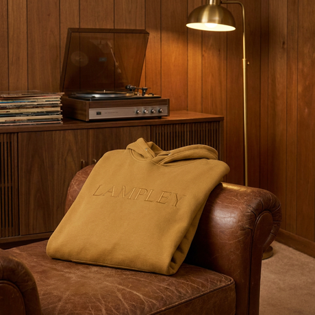 Gold LAMPLEY hoodie folded on a vintage leather armchair
