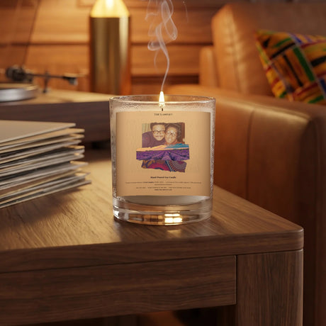 The Lampley 11oz hand-poured soy tribute candle lit on a walnut side table beside vinyl records in a warm wood-paneled den
